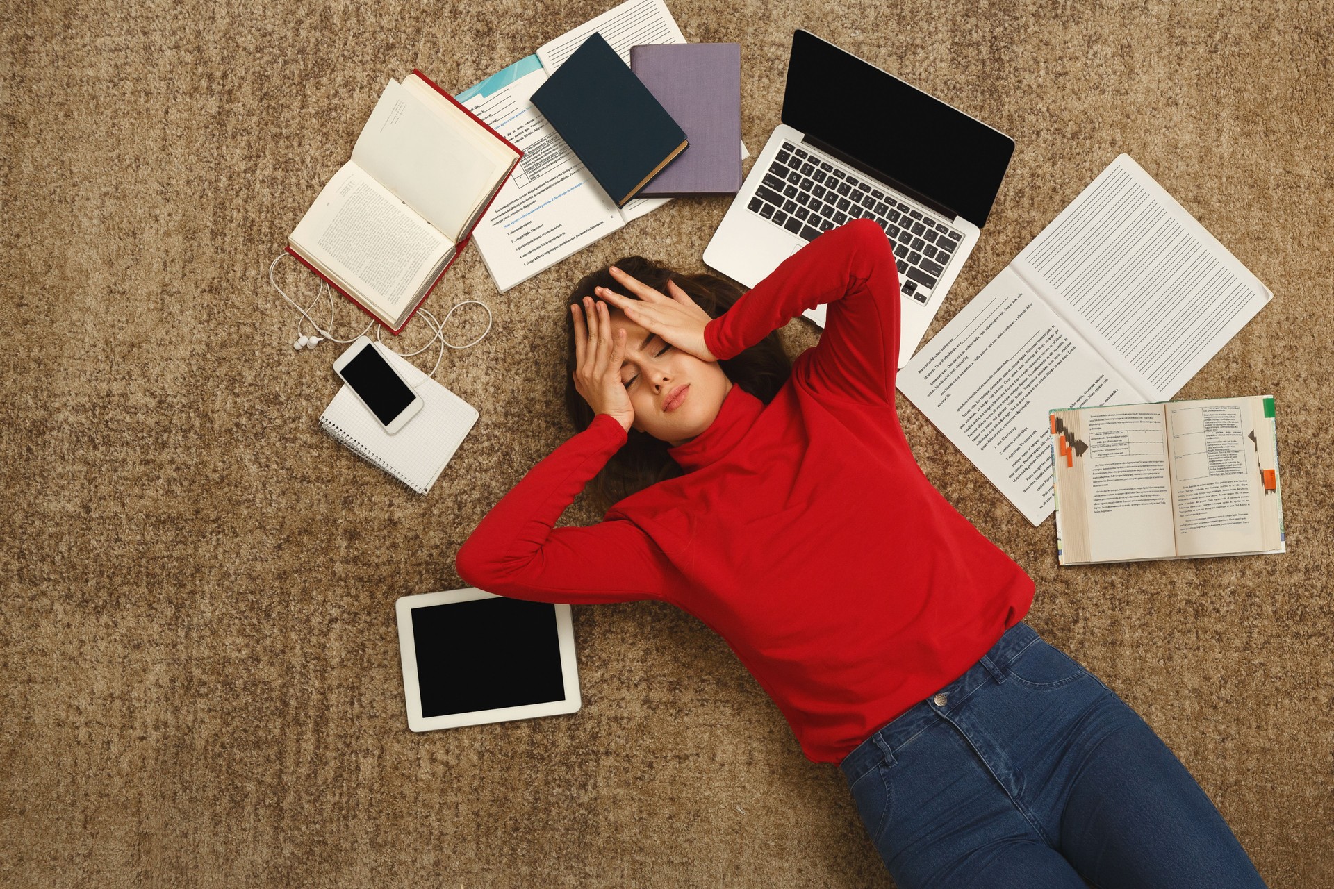 Chica estudiante cansado tirado en el suelo con libros y gadgets